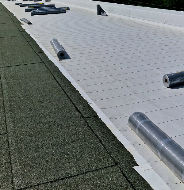 Commercial flat roof with green and white membrane for storm damage restoration.