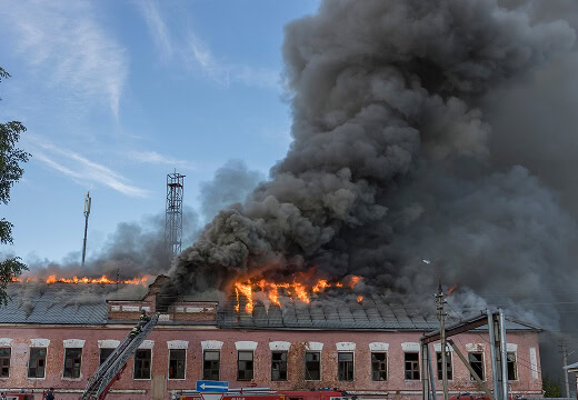 Firefighters battle flames and smoke on a flat roof during large-loss commercial roofing restoration.