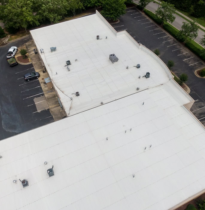 Aerial view of a commercial building with a flat white roof for large-loss storm damage restoration and commercial roofing services.