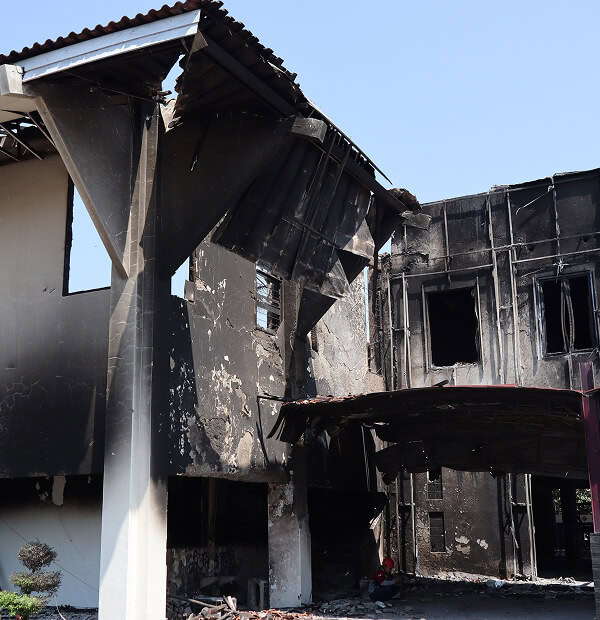 A fire-damaged commercial flat roof with blackened walls, broken windows, and large-loss restoration needs.