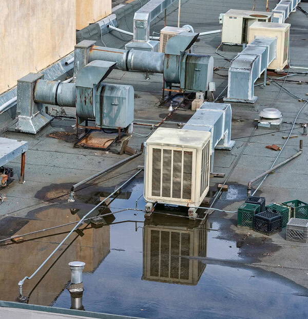 Flat commercial roof with HVAC units, storm damage puddles, ductwork, and vents.