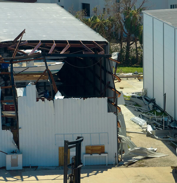 Commercial building with flat roof shows major storm damage needing large-loss recovery and commercial reroofing.