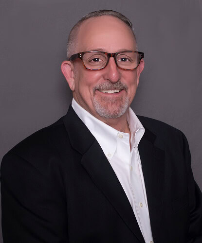 A middle-aged man in business attire, expert in commercial roofing and storm damage restoration.