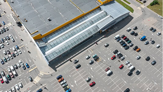 Aerial view of a retail store with a flat commercial roof and large parking lot, ideal for storm damage restoration or large-loss recovery.