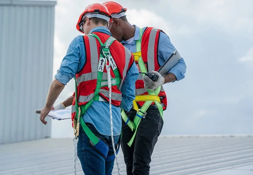 Commercial roofing crew in safety gear on flat roof review storm damage restoration plans.
