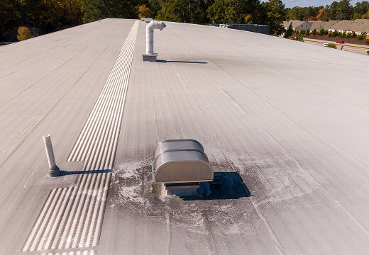 Flat commercial roof with HVAC units, showing light-colored membrane and vent stains; ideal for large-loss recovery or commercial reroofing.