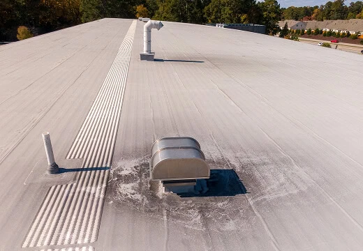 Flat commercial roof with HVAC units, showing light-colored membrane and vent stains; ideal for large-loss recovery or commercial reroofing.