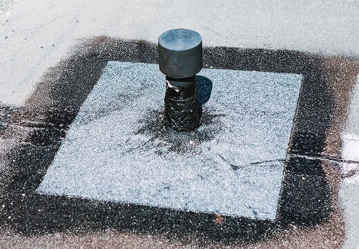 Commercial roofing flat roof with vent pipe and sealant for large-loss restoration.