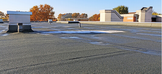 Flat commercial roof with bitumen, seams, vents, HVAC; ideal for large-loss recovery and commercial reroofing.