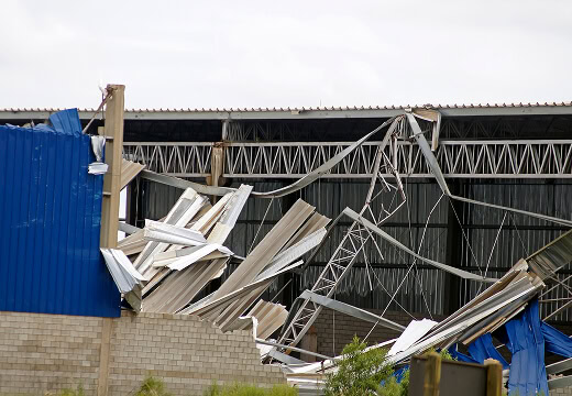 Collapsed industrial building showing storm-damaged flat roof and commercial reroofing needs.