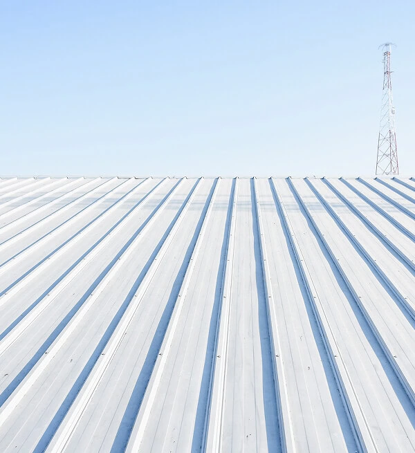 A white commercial metal flat roof under a blue sky, ideal for large-loss storm restoration.