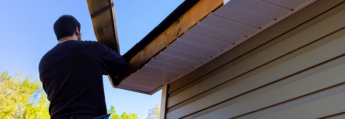 A technician repairs soffit and fascia during a commercial roofing large-loss restoration.