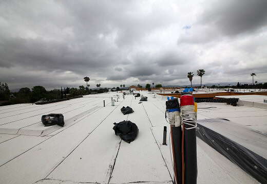 Flat commercial roof with white membrane, HVAC units, and storm damage restoration in process.