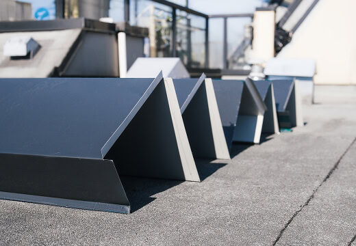 Four metal ventilation units on a commercial flat roof with large-loss restoration equipment.