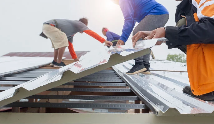 Commercial roofing crew installs metal panels for large-loss storm damage restoration.