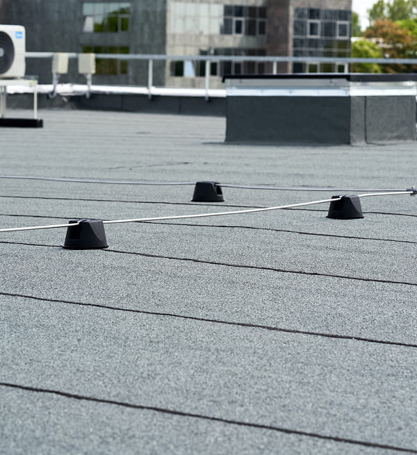 Flat commercial roofing with safety cable system, stanchions, and rooftop units for storm damage restoration and large-loss recovery.