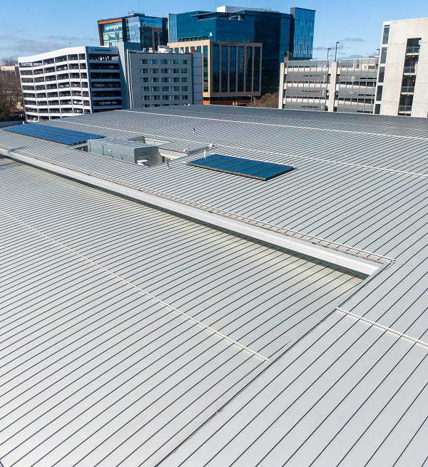 Commercial roofing flat metal roof with solar panels and large-loss restoration in progress.